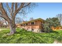 Well-maintained home featuring a brick exterior, green lawn, and mature trees at 6773 E Baker Pl, Denver, CO 80224