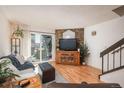 Bright living room featuring hardwood floors, a stone accent wall, and sliding glass doors to the outside at 3506 S Depew St # 3, Denver, CO 80235
