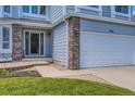 Home facade featuring brick accents, a two-car garage and an entrance framed by sidelights at 10155 Silver Maple Cir, Highlands Ranch, CO 80129
