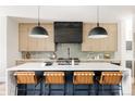 Modern kitchen with large island, tan leather bar stools, stainless appliances and light wood cabinets at 732 S Gaylord St, Denver, CO 80209