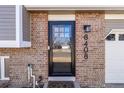 Close-up view of the front door and house number, highlighting brickwork and exterior lighting fixture at 8408 Wild Alfalfa Pl, Parker, CO 80134