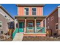 Charming two-story home features a welcoming front porch with teal railing and a vibrant coral exterior at 10331 E 62Nd Pl, Denver, CO 80238