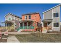 Charming two-story home features a welcoming front porch with teal railing and a vibrant coral exterior at 10331 E 62Nd Pl, Denver, CO 80238