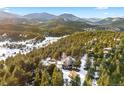 Aerial view of a secluded home nestled among pine trees and snow-dusted mountains in the background at 1056 County Road 65, Evergreen, CO 80439