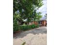 Exterior of a red brick home with a concrete driveway and mature trees at 938 Salem St, Aurora, CO 80011