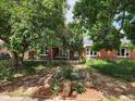 Landscaped front yard featuring a brick walkway, garden, and mature trees shading a brick home at 938 Salem St, Aurora, CO 80011