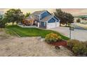Charming two-story blue home featuring an attached three-car garage, a sprawling lawn, and a delightful outdoor living space at 7071 S Gibraltar Way, Centennial, CO 80016