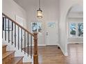Inviting foyer featuring hardwood floors, staircase, and an arched doorway to the living spaces at 7071 S Gibraltar Way, Centennial, CO 80016
