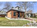 Charming brick home featuring a cozy front porch and manicured lawn at 4673 Bryant St, Denver, CO 80211