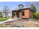 Charming brick home featuring a cozy front porch and manicured lawn at 4673 Bryant St, Denver, CO 80211