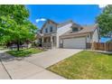 Two-story home with a manicured lawn, mature trees, and a wide driveway leading to an attached garage at 11256 Lima St, Commerce City, CO 80640