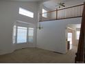 Bright living room featuring an open floor plan with neutral paint, large windows, and a view of the second-story railing at 3930 S Quatar St, Aurora, CO 80018