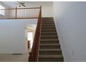 Carpeted staircase with wooden railing leads to the second floor, complemented by natural light and a neutral color scheme at 3930 S Quatar St, Aurora, CO 80018