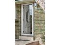 White front door with storm door and brick exterior at 11921 W 70Th Pl, Arvada, CO 80004