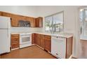 Functional kitchen with white appliances, wood cabinets, and window with a view of the sunroom at 10450 W 81St Pl, Arvada, CO 80005