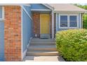 Entryway featuring a bright yellow front door, brick columns, and well-maintained landscaping at 9917 Garland Dr, Broomfield, CO 80021