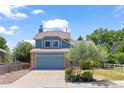 Traditional two-story home with a blue exterior, brick details, and a well-maintained lawn with mature landscaping at 9917 Garland Dr, Broomfield, CO 80021