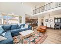 Bright living room features a soaring ceiling, large windows, hardwood floors, and an open concept layout to kitchen and dining room at 1282 Eldorado Dr, Superior, CO 80027