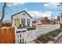 Charming white home with black trim, a bright yellow door, and a well-manicured front yard at 4883 Perry St, Denver, CO 80212