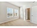 Light-filled bedroom with neutral carpeting, two windows, and a closet for ample storage at 2997 Pershing St, Strasburg, CO 80136