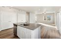 Open-concept kitchen and living room with wood flooring, natural light, stainless steel dishwasher, and ceiling fan at 2997 Pershing St, Strasburg, CO 80136