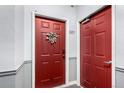 Red apartment door, number 307, adorned with a floral wreath and flanked by a second red door in a neutral hallway at 4451 S Ammons St # 5-307, Littleton, CO 80123