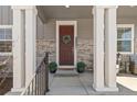 Close-up of the front door with stylish stone accents and elegant white columns and brickwork at 9080 W 100Th Way, Broomfield, CO 80021