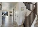 Bright hallway with wood floors leading to an open-concept living area and staircase with wood banister at 14290 Hop Clover St, Parker, CO 80134