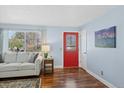 Bright living room features a decorative red door, hardwood floors, and a large window at 6074 S Dudley Way, Littleton, CO 80123