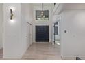 Bright and airy foyer with a modern light fixture, sleek black double doors, and light hardwood floors at 5951 S Akron Way, Greenwood Village, CO 80111