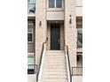 A close-up of the front entrance featuring a large black door, brick facade, and concrete stairs at 32 Jackson St, Denver, CO 80206
