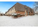 Exterior view showcasing a two-story building with stone and siding details, plus snowy landscaped grounds at 9650 Huron St # 22, Thornton, CO 80260