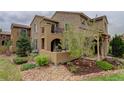 Exterior elevation with stone features, a balcony, a stucco-covered patio, and well-maintained yard and landscaping at 9592 Firenze Way, Highlands Ranch, CO 80126
