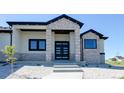 Close up of exterior featuring stone accents, a modern front door, and well-manicured landscaping at 56520 E 74Th Ave, Strasburg, CO 80136
