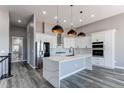 Modern kitchen with white cabinets, quartz countertops, stainless steel appliances, and stylish pendant lighting at 56520 E 74Th Ave, Strasburg, CO 80136