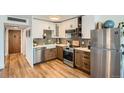 Well-lit kitchen featuring stainless steel appliances, shaker cabinets, wood-look flooring, and tile backsplash at 790 N Washington St # 1003, Denver, CO 80203