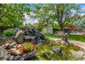 Landscaped backyard with stone waterfall, pond, and wooden shed at 3525 S Brentwood St, Lakewood, CO 80235