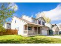 Attractive two-story home with covered porch and manicured lawn on a sunny day at 13812 W 64Th Pl, Arvada, CO 80004