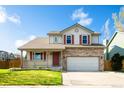 Inviting two-story home features red shutters, a covered porch, and an attached garage at 13812 W 64Th Pl, Arvada, CO 80004