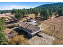 Stunning aerial view of a home with a spacious deck, outbuildings and scenic wooded surroundings at 87 Elmgreen Ln, Evergreen, CO 80439