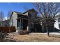 Two-story home with front yard and large shade tree with covered front porch with stone accents at 9121 Harlequin Cir, Frederick, CO 80504