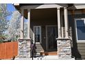 Inviting front entrance with stone pillars and dark trim creating a warm and welcoming ambiance at 9121 Harlequin Cir, Frederick, CO 80504