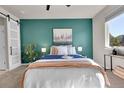 Stylish bedroom featuring a teal accent wall, plush bedding, and natural light from the window at 5179 S Fairplay St, Aurora, CO 80015
