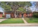 Inviting brick home with lush front yard, charming porch, and driveway leading to a detached garage at 1320 Quari St, Aurora, CO 80011