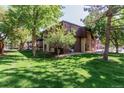 Beautiful apartment building with mature trees and green grass on a sunny day at 7755 E Quincy Ave # 308A5, Denver, CO 80237
