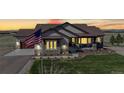 Inviting single-Gathering home at dusk with warm interior lights, complemented by an American flag at 220 High Meadows Loop, Elizabeth, CO 80107