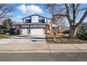 Charming two-story home featuring a three-car garage, blue trim, brick accents, and mature trees in a well-maintained neighborhood at 15974 E Loyola Dr, Aurora, CO 80013