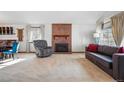 Spacious living room featuring a fireplace, large windows with curtains, carpeted flooring, a gray sofa, and a swivel recliner at 15974 E Loyola Dr, Aurora, CO 80013