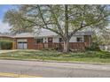 Charming brick home with a large tree, a red front door, and an attached garage offers great curb appeal at 2201 S Lowell Blvd, Denver, CO 80219