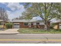 Charming brick home with a large tree, a red front door, and an attached garage offers great curb appeal at 2201 S Lowell Blvd, Denver, CO 80219